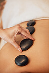 Hands, rock and spa for back massage in relax for healthy wellness, zen or physical therapy treatment at resort. Hand of therapist applying rocks in relaxation, stress relief and luxury care for skin