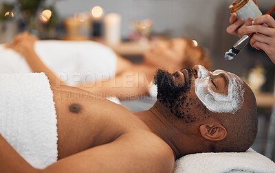 Buy stock photo Skincare, wellness and black man getting a facial at a spa for relaxation, calm and satisfaction. Beauty, luxury treatment and couple massage at beauty salon together, skincare products on man's face