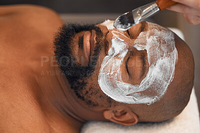 Buy stock photo Facial, skincare and relax with black man in spa for beauty, luxury and mud mask. Wellness, therapy and health with male and beautician brush cosmetics product on face for peace, massage and salon