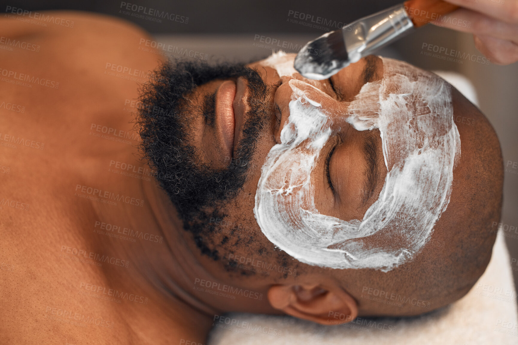 Buy stock photo Facial, skincare and relax with black man in spa for beauty, luxury and mud mask. Wellness, therapy and health with male and beautician brush cosmetics product on face for peace, massage and salon