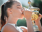 Sport, winner and woman kiss trophy after tennis game success with sports achievement and fitness outdoor. Exercise, win and young athlete celebrating victory, competition champion and active.
