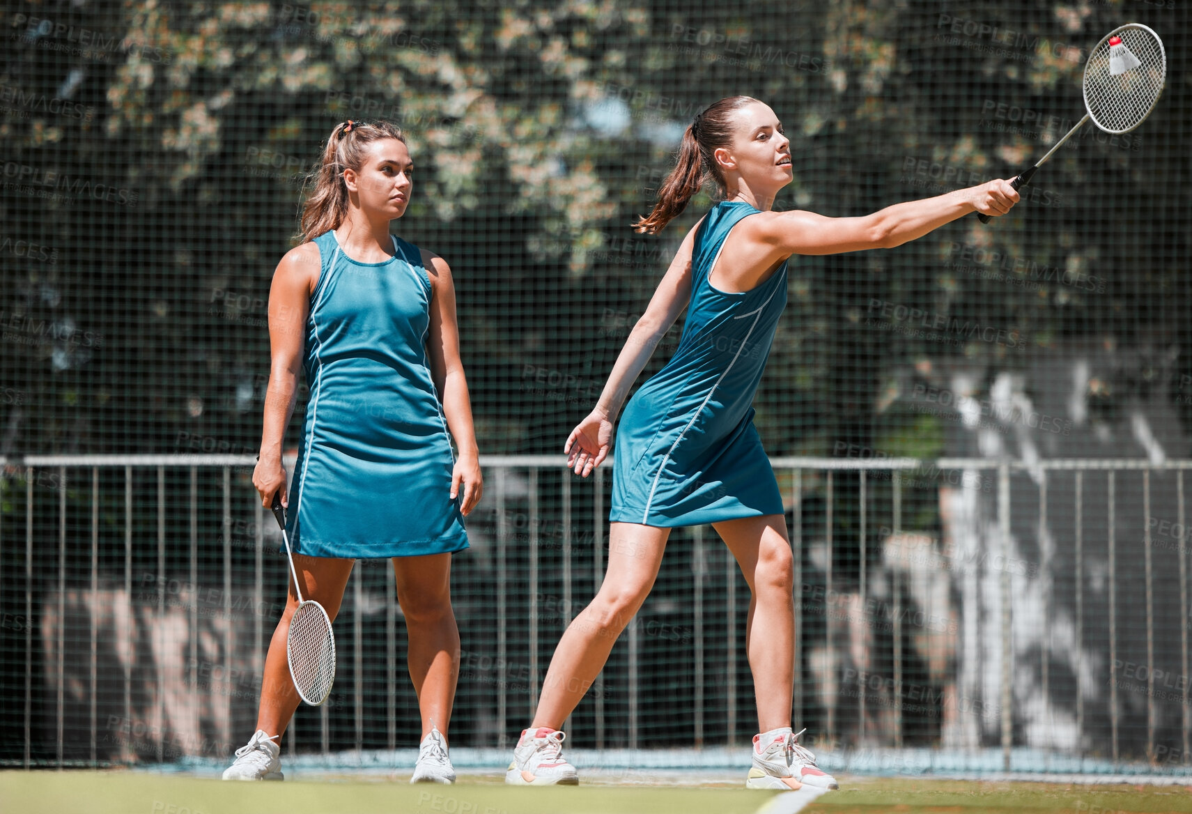 Buy stock photo Badminton, sports and women with a serve on an outdoor court busy with fitness and exercise. People training, cardio and athlete workout of sport student teamwork and collaboration together