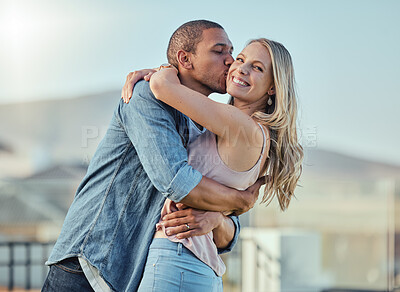 Buy stock photo Interracial man and woman, love and kiss outside feeling happy, in love and caring in the city. Romance, romantic and boyfriend and girlfriend embracing, hugging and kissing with affection in town