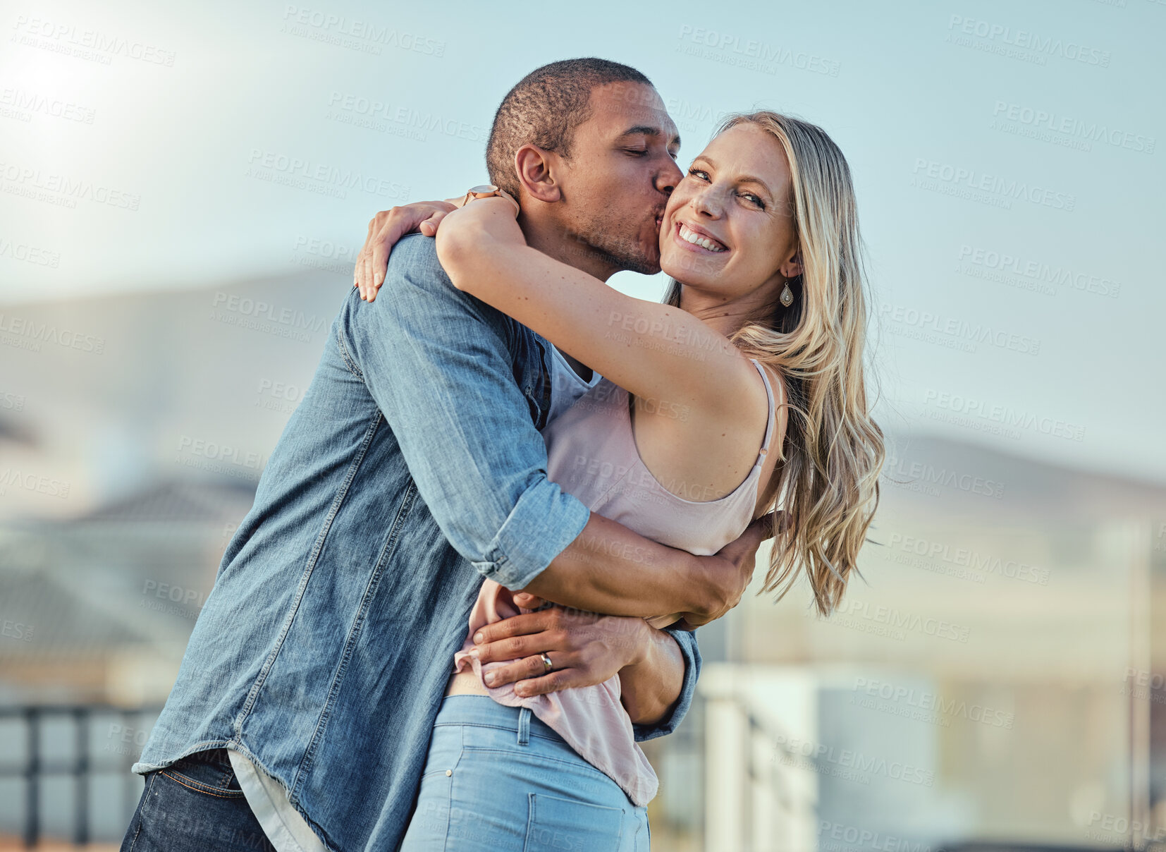 Buy stock photo Interracial man and woman, love and kiss outside feeling happy, in love and caring in the city. Romance, romantic and boyfriend and girlfriend embracing, hugging and kissing with affection in town