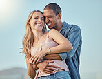 Interracial couple, smile hug outdoor and happy together for honeymoon, vacation or summer travel. Black man embrace, caucasian woman with happiness on face and love, romance or bonding in sunshine