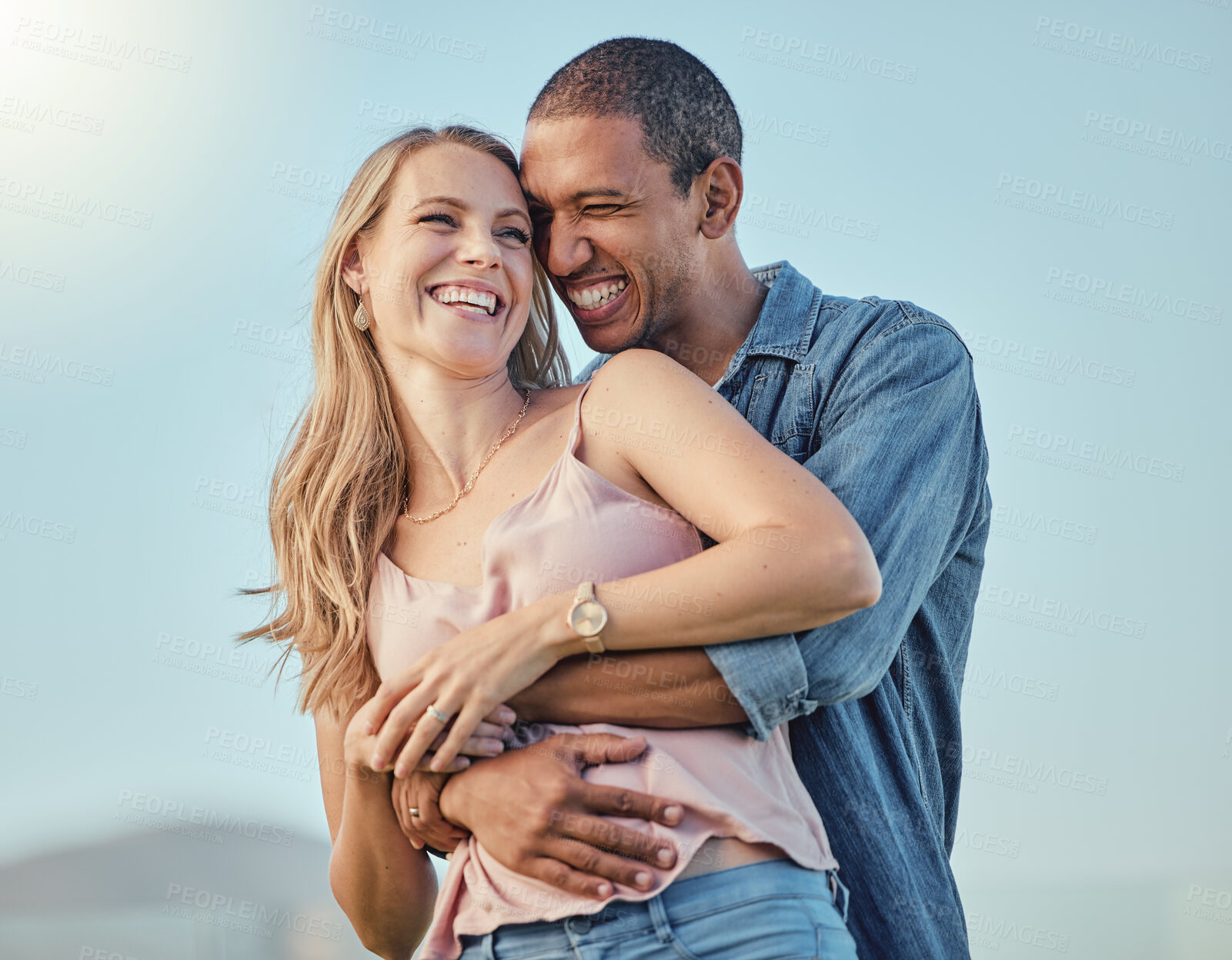 Buy stock photo Interracial couple, smile hug outdoor and happy together for honeymoon, vacation or summer travel. Black man embrace, caucasian woman with comic happiness and love, romance or bonding in sunshine