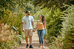 Couple, hand holding and nature park walking of people on a outdoor path with a smile. Happy girlfriend and boyfriend together showing love, care and commitment on a walk or hike feeling happiness