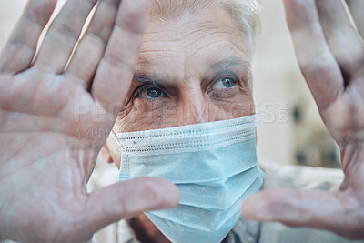Buy stock photo Hands, covid and quarantine with a senior man in a mask standing behind glass in a house during lockdown. Window, sad and isolated with a mature male in a retirement home during corona virus pandemic