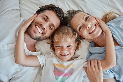 Buy stock photo Family, children and face with a girl, mother and father lying on a bed together in their home in the morning. Portrait, bedroom and bonding with a man, woman and daughter in the bedroom from above