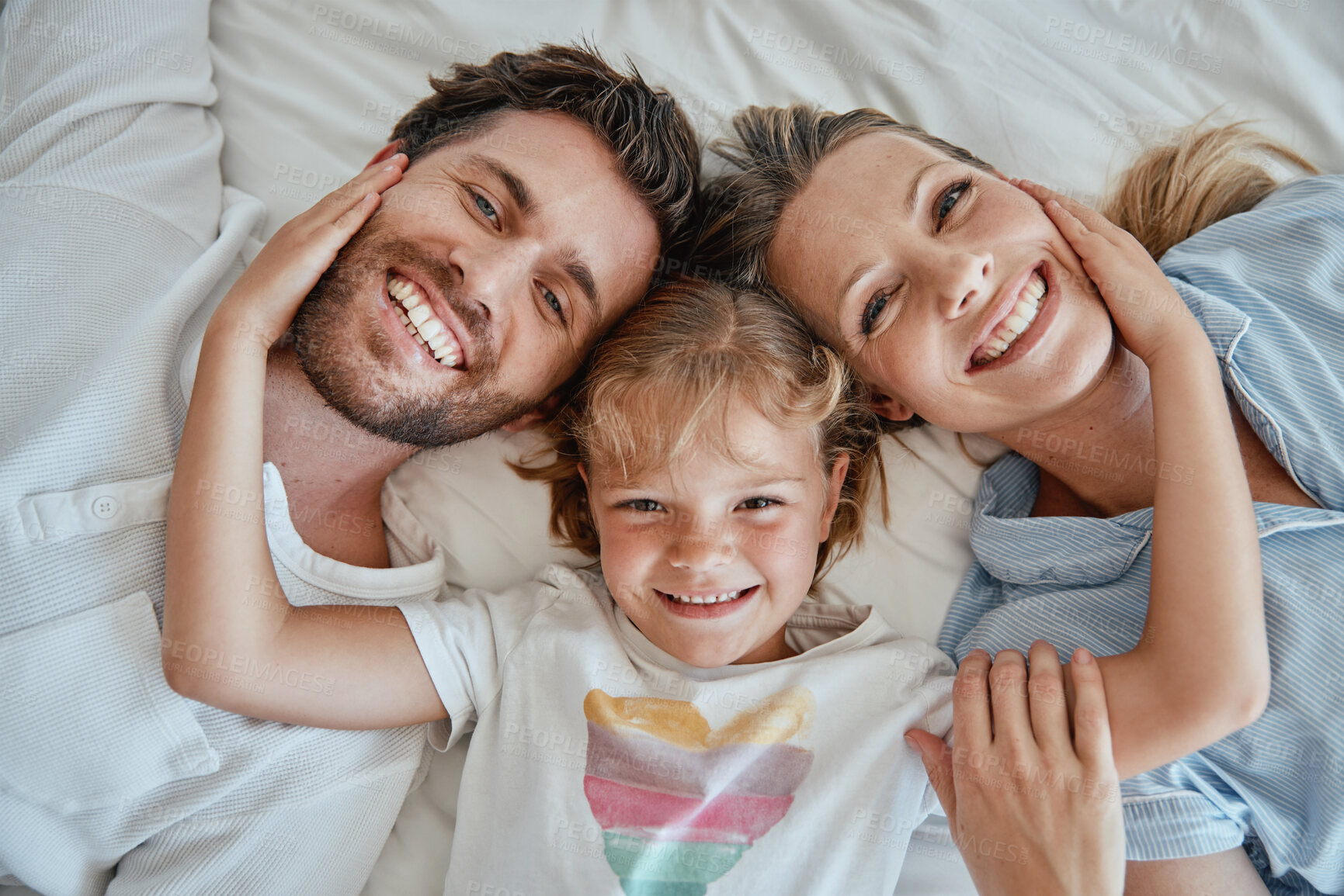 Buy stock photo Family, children and face with a girl, mother and father lying on a bed together in their home in the morning. Portrait, bedroom and bonding with a man, woman and daughter in the bedroom from above