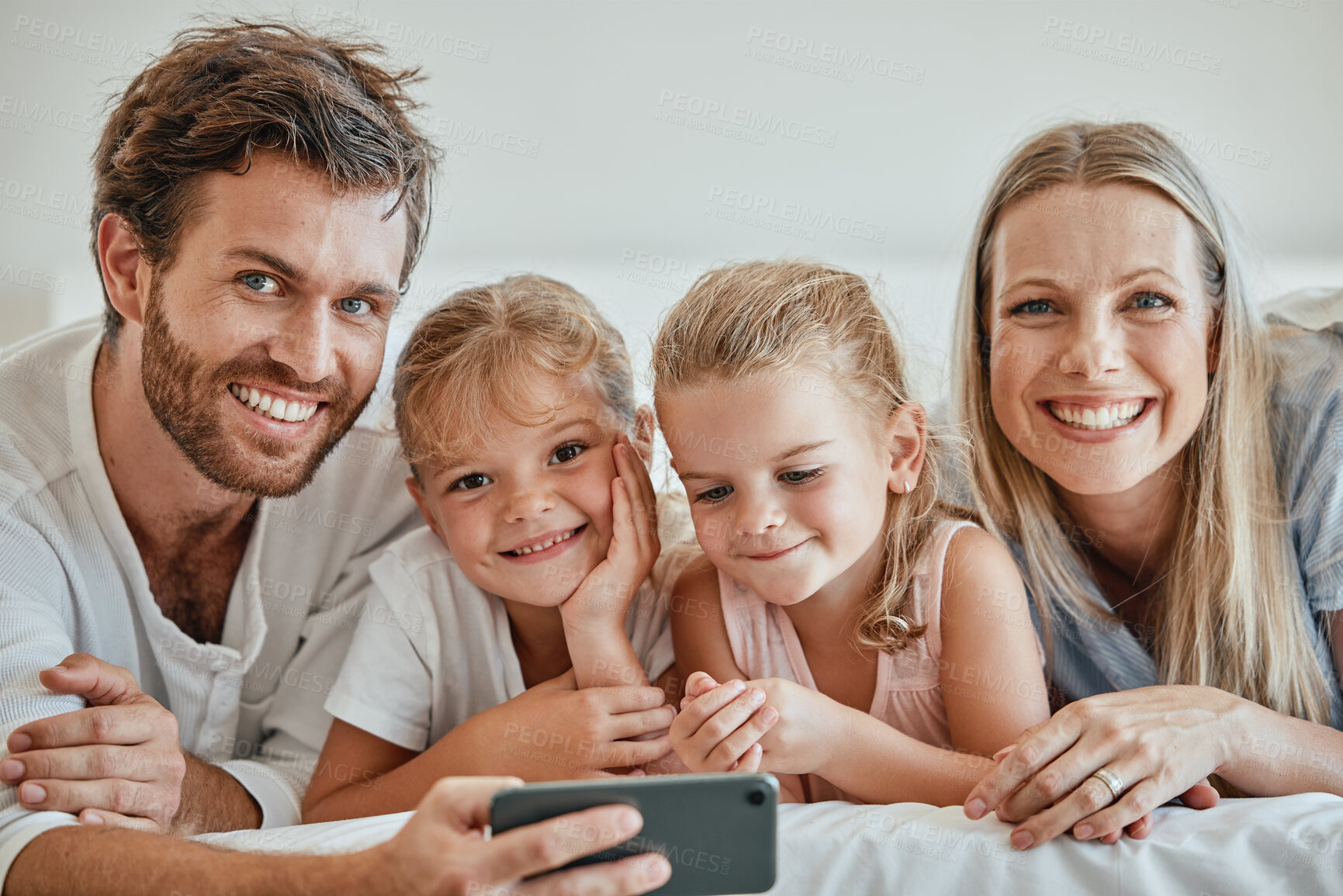 Buy stock photo Family, phone and bed with a girl, sister and parents bonding together in the bedroom of the home in the morning. Children, portrait and mobile with a man, woman and daughter siblings lying on a bed