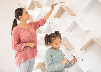 Buy stock photo Glasses, decision and mother and child at an optometrist clinic for choice of frame for vision together. Optometry, smile and girl and mom with eyeglasses for eyes as a customer choosing in a store