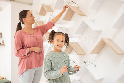 Buy stock photo Optometry, mother and child with decision on glasses for vision, smile and help with eyes at a clinic. Happy, consulting and girl kid patient at the optometrist for eyeglasses with her mom helping
