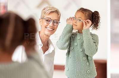 Buy stock photo Eyes, consulting and glasses by girl and optometrist woman at optician store for choice, fitting and eye test. Eyesight, eyeglasses and ophthalmologist and child consultation, eye care and vision