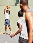 Fitness, basketball and basketball player shooting in a training game, sports exercise or workout outdoors. Wellness, focus and healthy men enjoy playing on a basketball court as friends in Nigeria