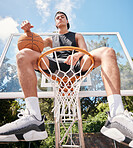 Sports, basketball and man sitting on basketball hoop and preparing for training, match or competition outdoors on basketball court. Portrait, basketball player and male on rim ready for exercise.