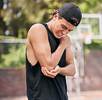 Sport injury, basketball and man in pain while playing on basketball court, fitness and hurt elbow outdoor. Young athlete holding arm, sore and exercise accident, sports and training in park.