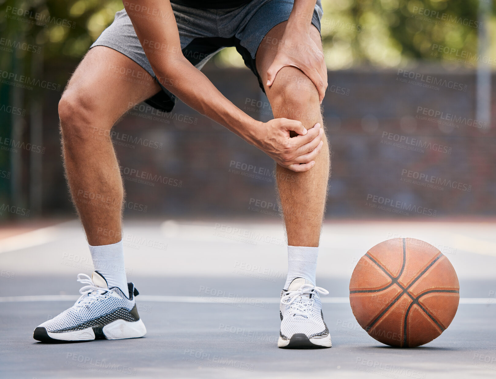Buy stock photo Pain, basketball and man with knee injury standing on outdoor court, holding leg. Sports, fitness and athlete with joint pain, injured and hurt in training, workout and game on basketball court