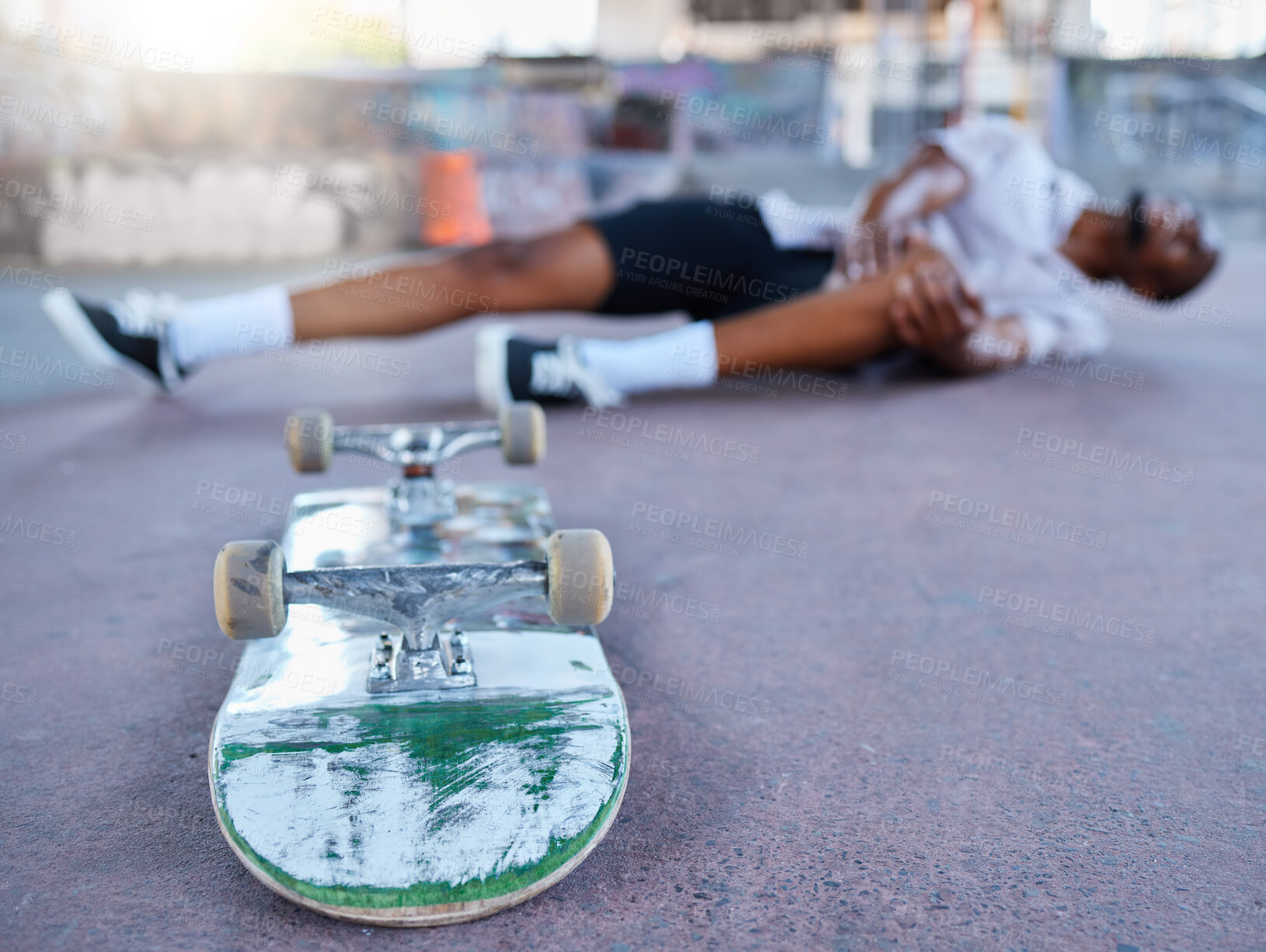 Buy stock photo Skateboard, skater and knee injury in street, city or outdoors after failed stunt or accident. Skateboarding, sports and black man with sore leg, joint inflammation or muscle pain at urban skate park