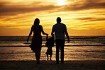 Silhouette, beach and family at the sea at sunset, holding hands and playing, bonding and relax together. Shadow, happy family and child with parents at sunrise, travel, freedom and love in Bali 