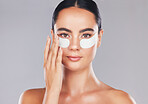 Skincare, face and woman with eye patches on a gray studio background. Health, beauty or female model from Spain with facial product, cosmetics pads or collagen eye mask for hydration or anti aging

