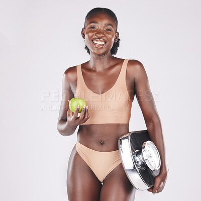 Buy stock photo Black woman, scale and apple to lose weight, healthy diet and fitness results, progress and exercise motivation isolated on studio background. Happy model eating fruit, nutrition and body wellness