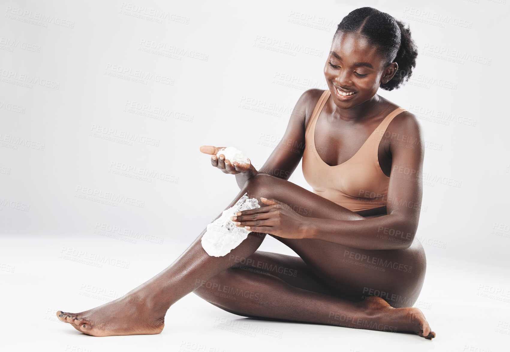 Buy stock photo Black woman, sitting with shaving cream on legs for skincare, cosmetics and skin wellness with smile. Happy african woman, grooming body hair and self care, self love and health by studio background