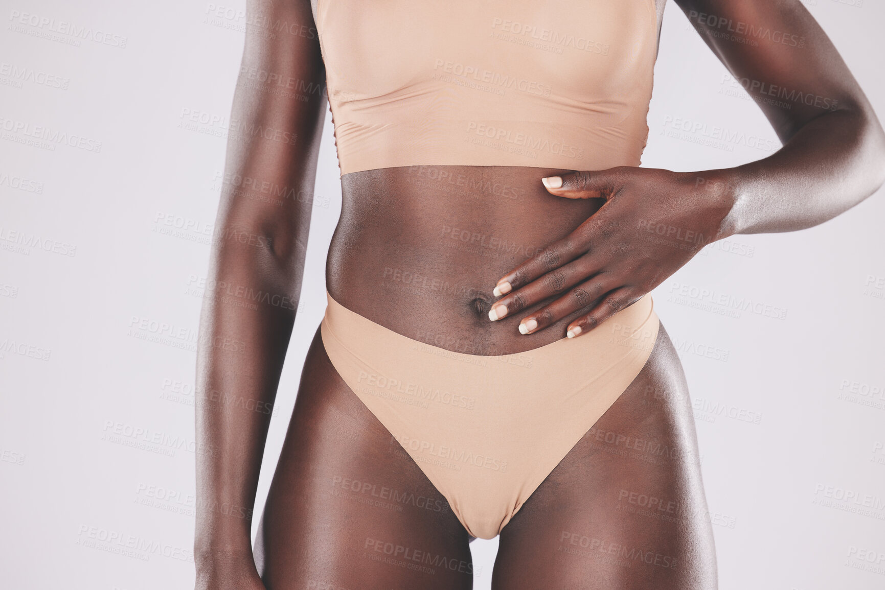 Buy stock photo Hand, stomach and body with a model black woman touching her tummy in studio on a gray background for wellness. Health, underwear and diet with a female posing for healthy eating or lifestyle