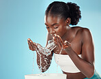 Water, wash and woman splashing her face for cleansing hygiene and skincare on a blue studio background. Skin care, body care and beauty female washing her for facial health and wellness