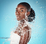 Splash, water and portrait of black woman for beauty, care of body and wellness against blue studio background. Health, skincare and African girl model cleaning with liquid for hygiene and grooming