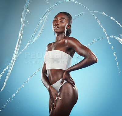 Buy stock photo Splash, beauty and black woman on blue background for wellness, skincare and shower, grooming and hygiene in studio. Wellness, water and model girl relax, zen and shower for body, skin and hydration