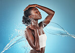 Water, cleaning and black woman with a splash on body, wellness and care with hydration against a blue studio background. Shower, luxury and African model with liquid for skincare and health