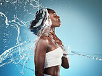 Water, splash and woman washing her body on a blue studio background for cleansing hygiene. Cleaning, wash and african american female using grooming treatment for hydration and bodycare 