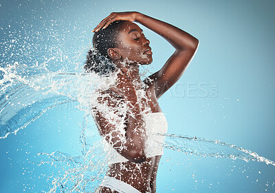 Buy stock photo Beauty, skincare and splash with water and black woman shower, hydration and moisture body care. Spa, wellness and health with girl model for luxury, natural and cosmetics in blue background studio