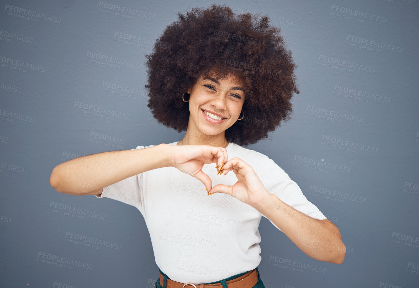 Buy stock photo Portrait, hand and heart with black woman in studio, happy and smile while relax against a grey background with mockup. Love, woman and hand shape by girl showing peace, care and emoji against a wall