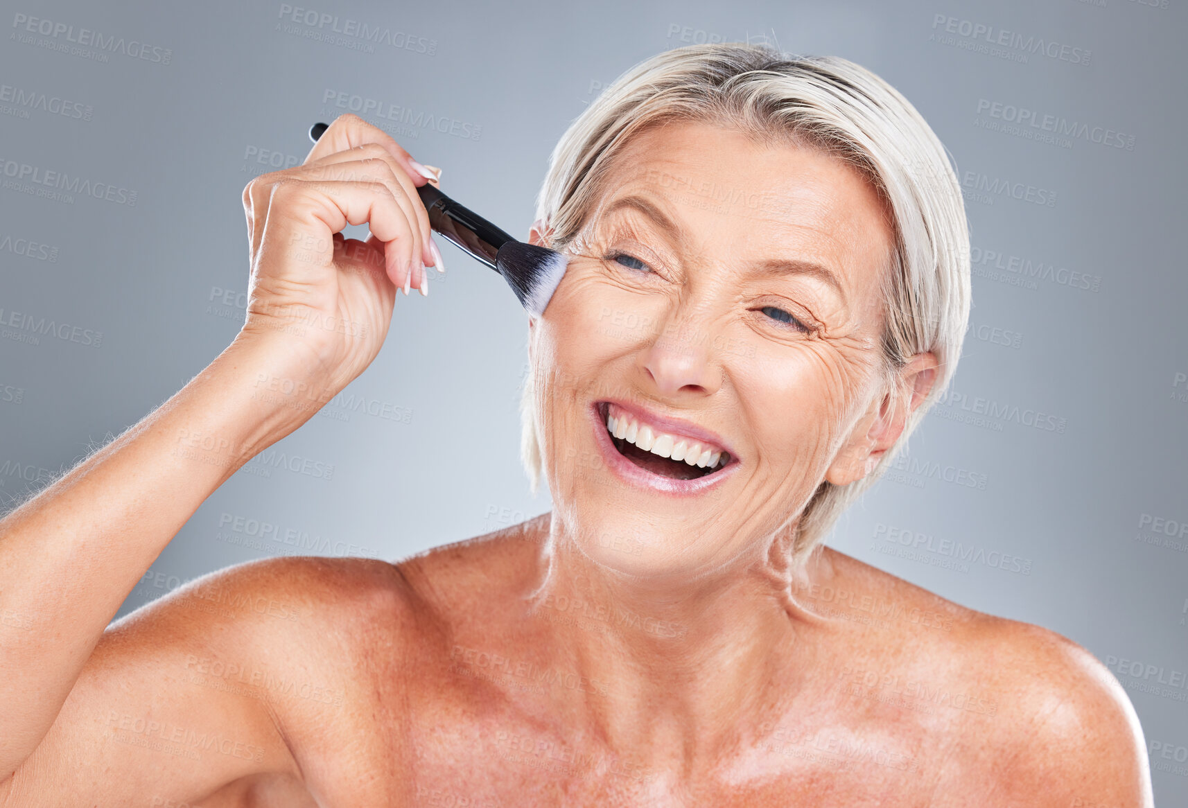 Buy stock photo Happy, senior woman and makeup brush in studio for beauty, skincare and wrinkles treatment on a grey background. Face, cheek and product by elderly model happy, excited and smiling about cosmetics