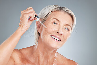 Buy stock photo Senior woman, skincare and serum for beauty, cosmetics or anti aging treatment against a grey studio background. Happy elderly female applying oil with dropper and smile in satisfaction for skin