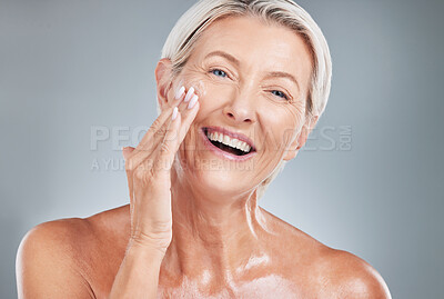 Buy stock photo Senior woman, beauty and smile for skincare, moisturizer or cosmetic treatment against a grey studio background. Happy elderly female smiling with teeth in satisfaction for perfect facial skin cream