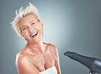 Hair care, happy and senior woman with a dryer for beauty, treatment and happiness against a grey mockup studio background. Cosmetic, smile and portrait of an elderly person with a hairdryer for hair