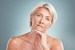 Senior woman, beauty and skincare with blue eyes posing for cosmetics against a grey studio background. Portrait of a confident isolated elderly female model in pose for anti aging facial treatment