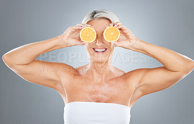 Beauty, skincare and orange with a model mature woman in studio on a gray background for health or wellness. Food, fruit and natural with an elderly female posing to promote nutrition or luxury