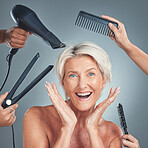 Hair care, excited and senior woman with hairdresser for beauty, haircut and preparation on grey studio background.  Happy, smile and surprise face of an elderly model with hands of stylist for hair