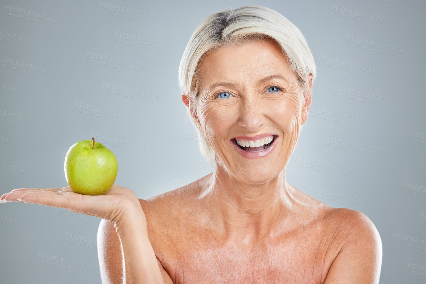 Buy stock photo Portrait, senior and woman with apple in studio for health, wellness and diet on a grey background mockup. Face, fruit and mature model happy, smile and relax, healthy lifestyle, detox and nutrition