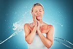 Water, splash and mature woman washing her body on a blue studio background for care and hygiene. Beauty, grooming and shower with a older female cleansing her skin for skincare and bodycare 