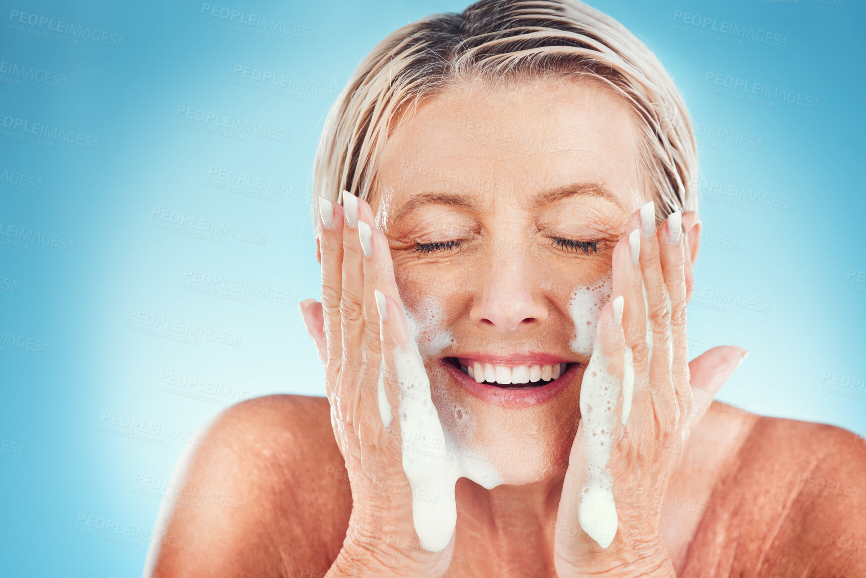 Buy stock photo Face, cleaning and senior woman washing, skin and water splash for wellness, beauty and skincare in a studio. Beauty splash, facial and elderly wellness model happy, smile and relax with soap product