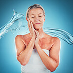 Skincare, water and senior woman with a splash for face beauty against a blue mockup studio background. Wellness, luxury and calm elderly model with facial care, hydration and natural dermatology