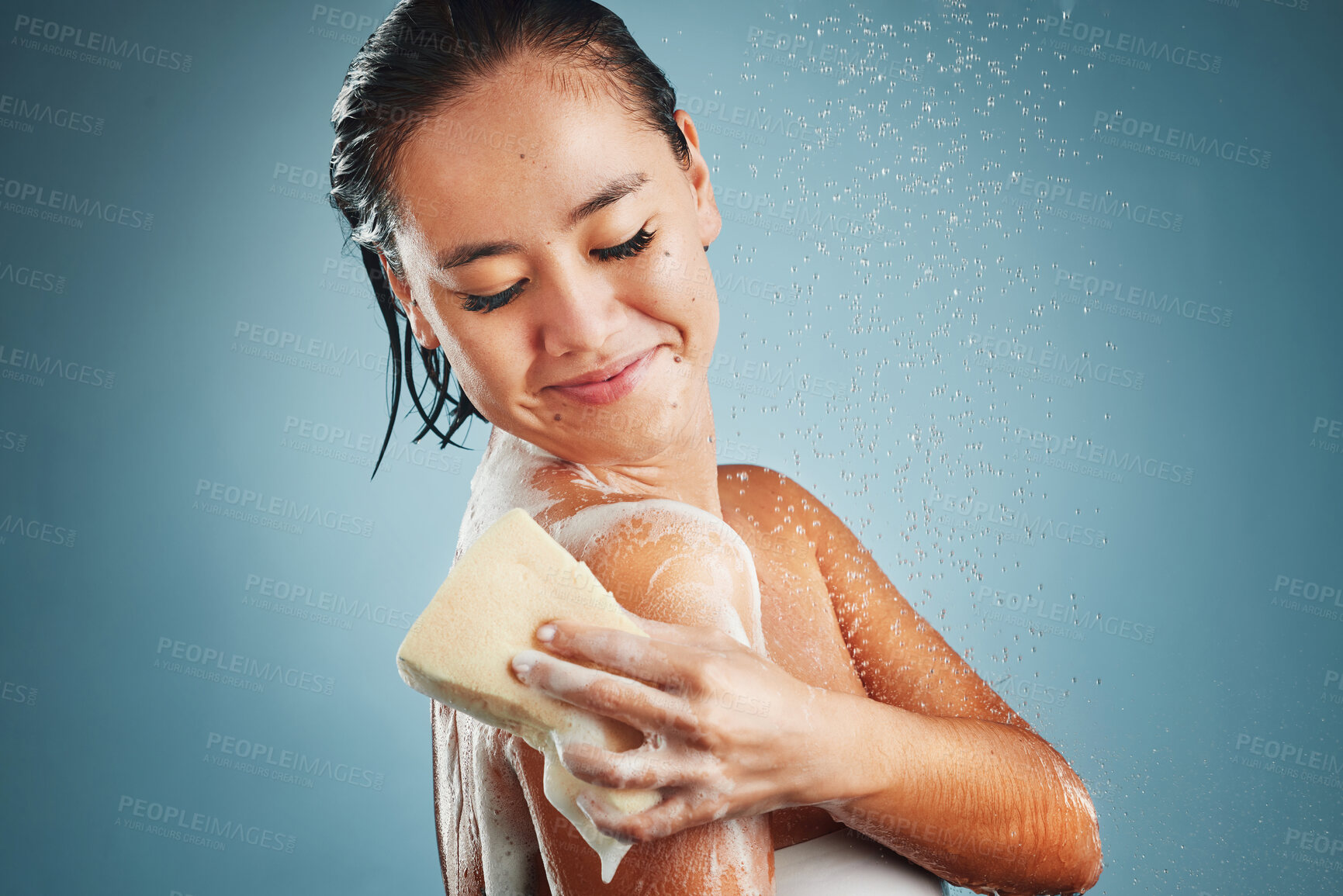 Buy stock photo Woman, water and happy skincare cleaning morning routine or skin wellness treatment with sponge. Young Asian girl washing, relax and healthy hygiene for cosmetic beauty care against blue background 