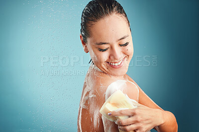 Buy stock photo Shower, sponge and soap with a woman cleaning her body in studio on a blue background with mockup. Water, hand and wellness with an attractive young female washing in the bathroom for hygiene