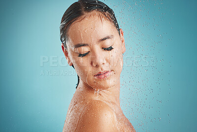 Buy stock photo Face, shower and cleaning with a woman in studio on a blue background for hygiene cleansing or hydrating. Water, bathroom and wellness with an attractive young female washing in a bathroom for care