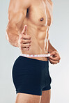 Fitness, thumbs up and man measuring body after training, workout and exercise. Healthy, wellness and strong muscular male with measuring tape on waist for diet, weight loss and body care in studio